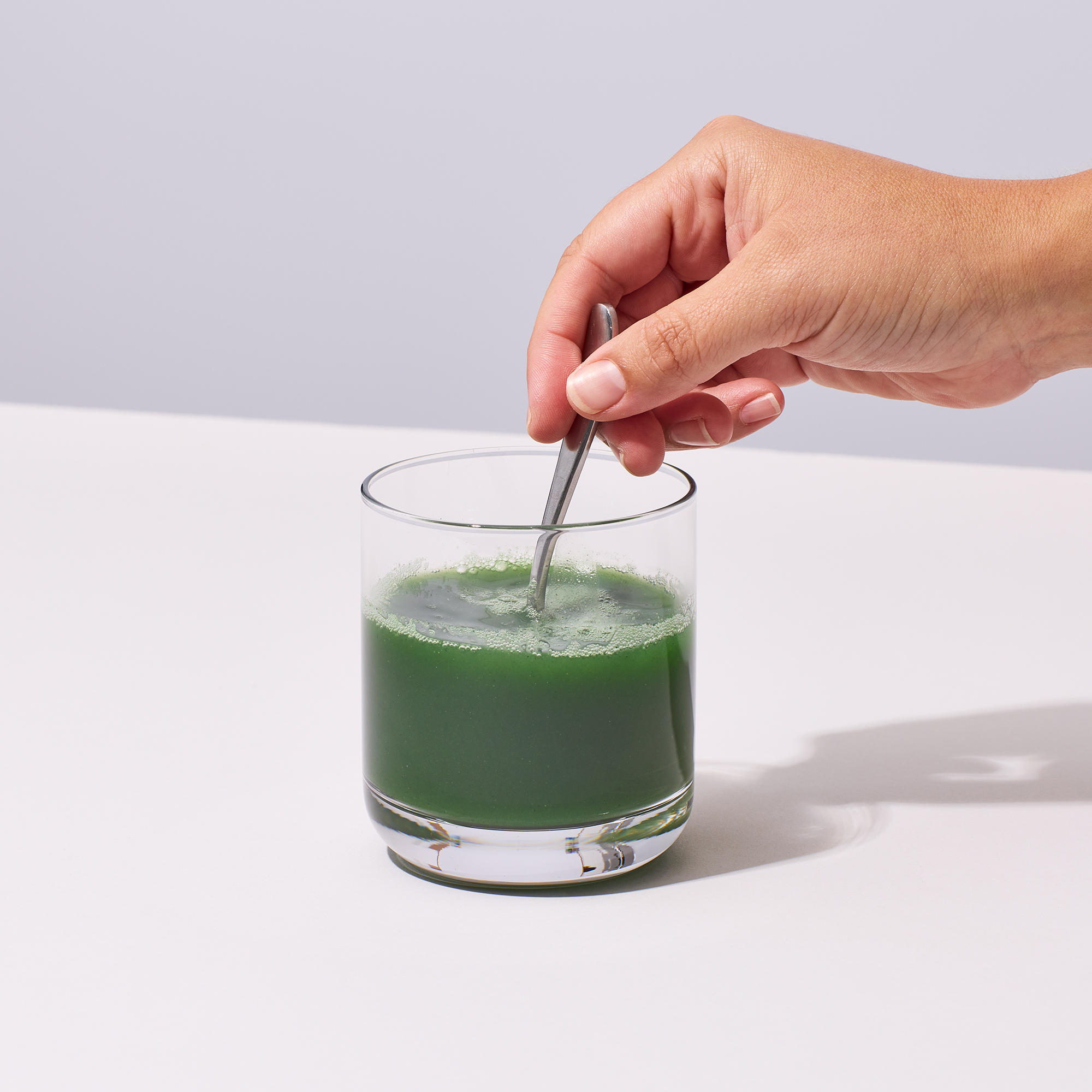 image of person adding water and mixing IX Complete Greens up in a glass