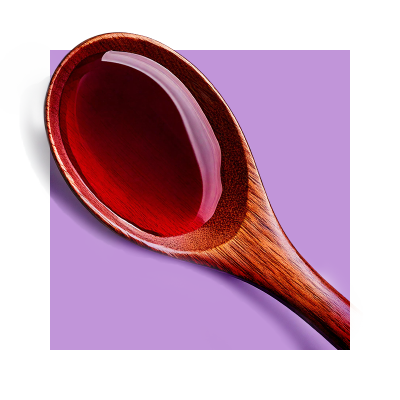 Image of wooden spoon with red wine extract dried against a purple background