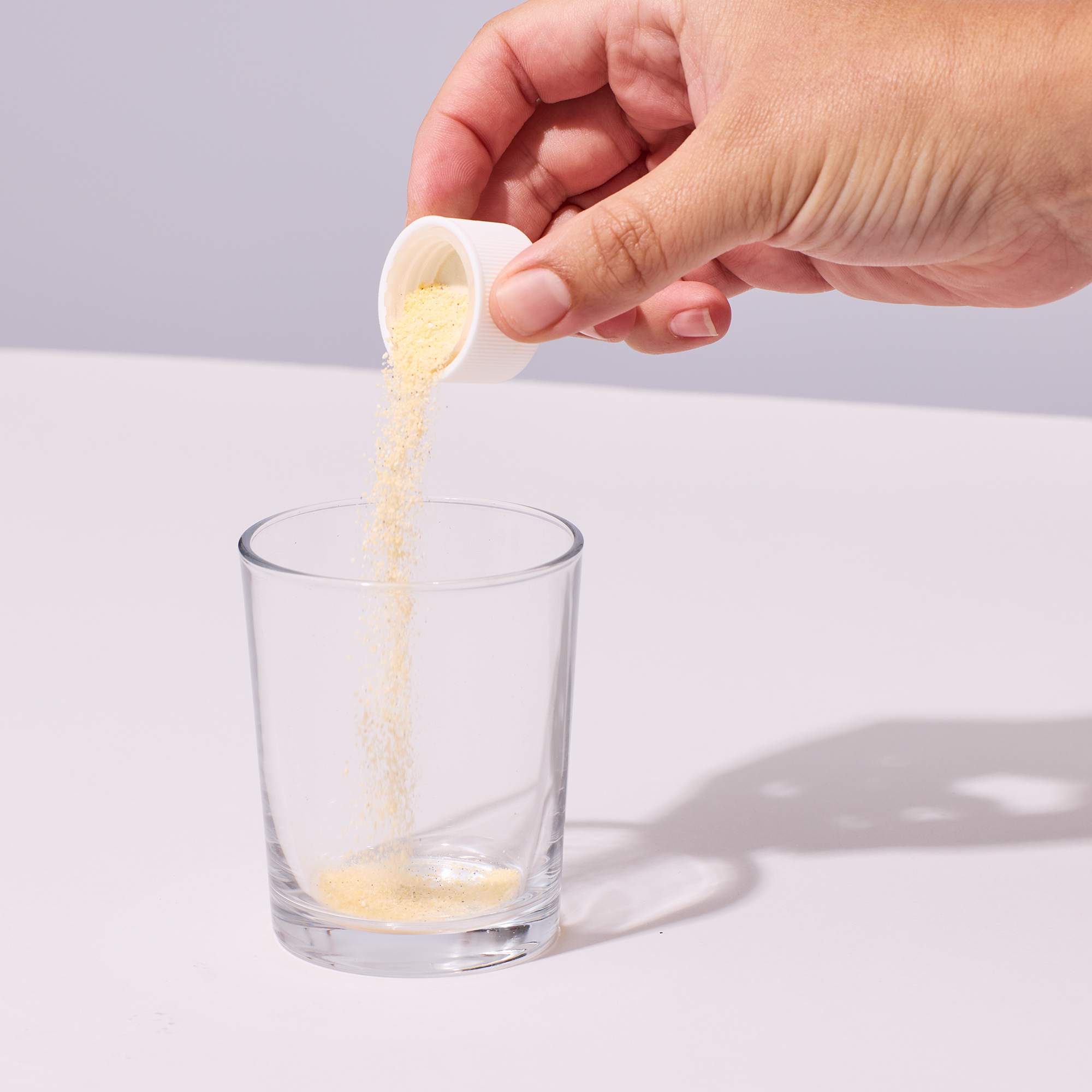 Image of person pouring Isotonix Multivitamin into a clear glass of water