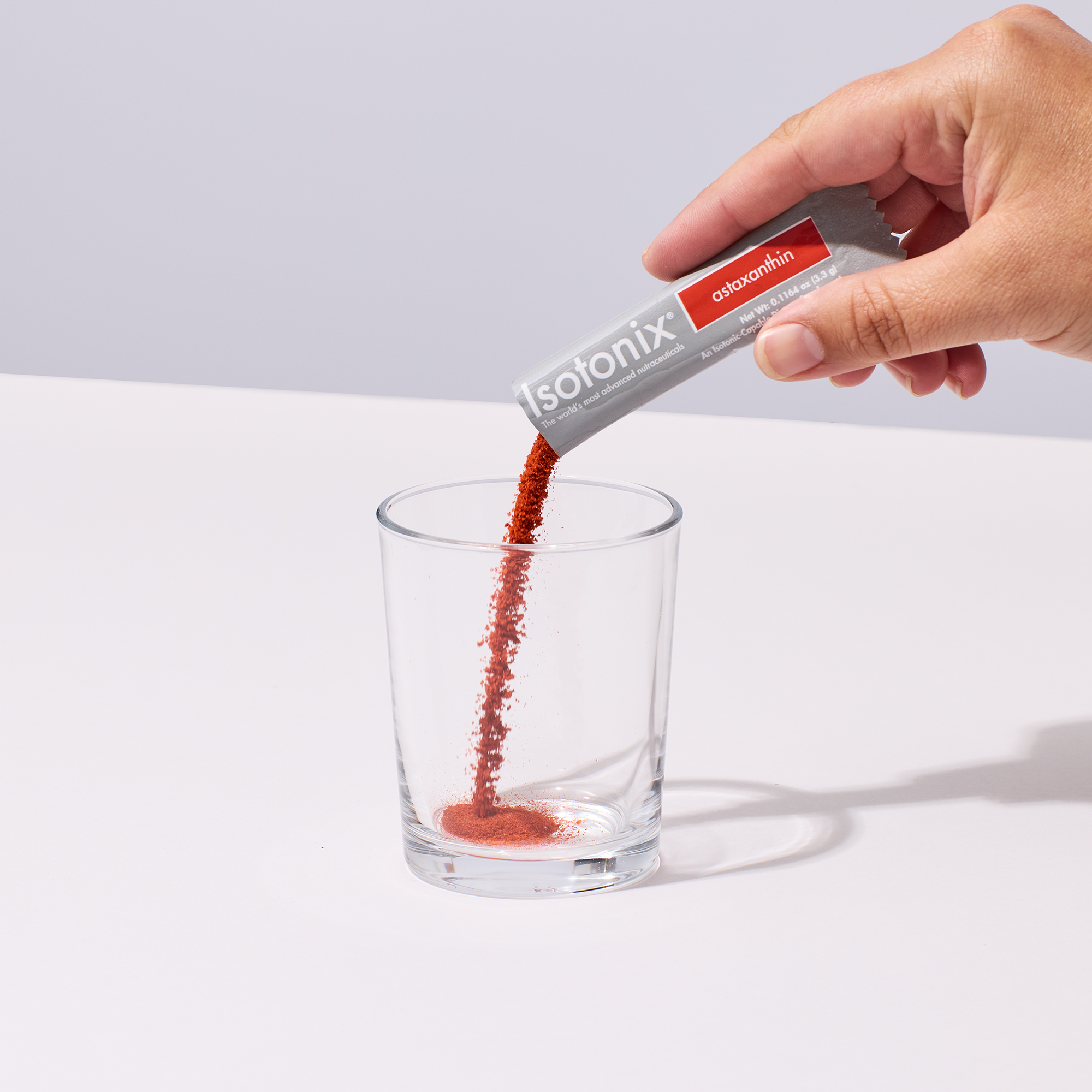 image of someone's hand pouring a serving of Isotonix Astaxanthin into a glass