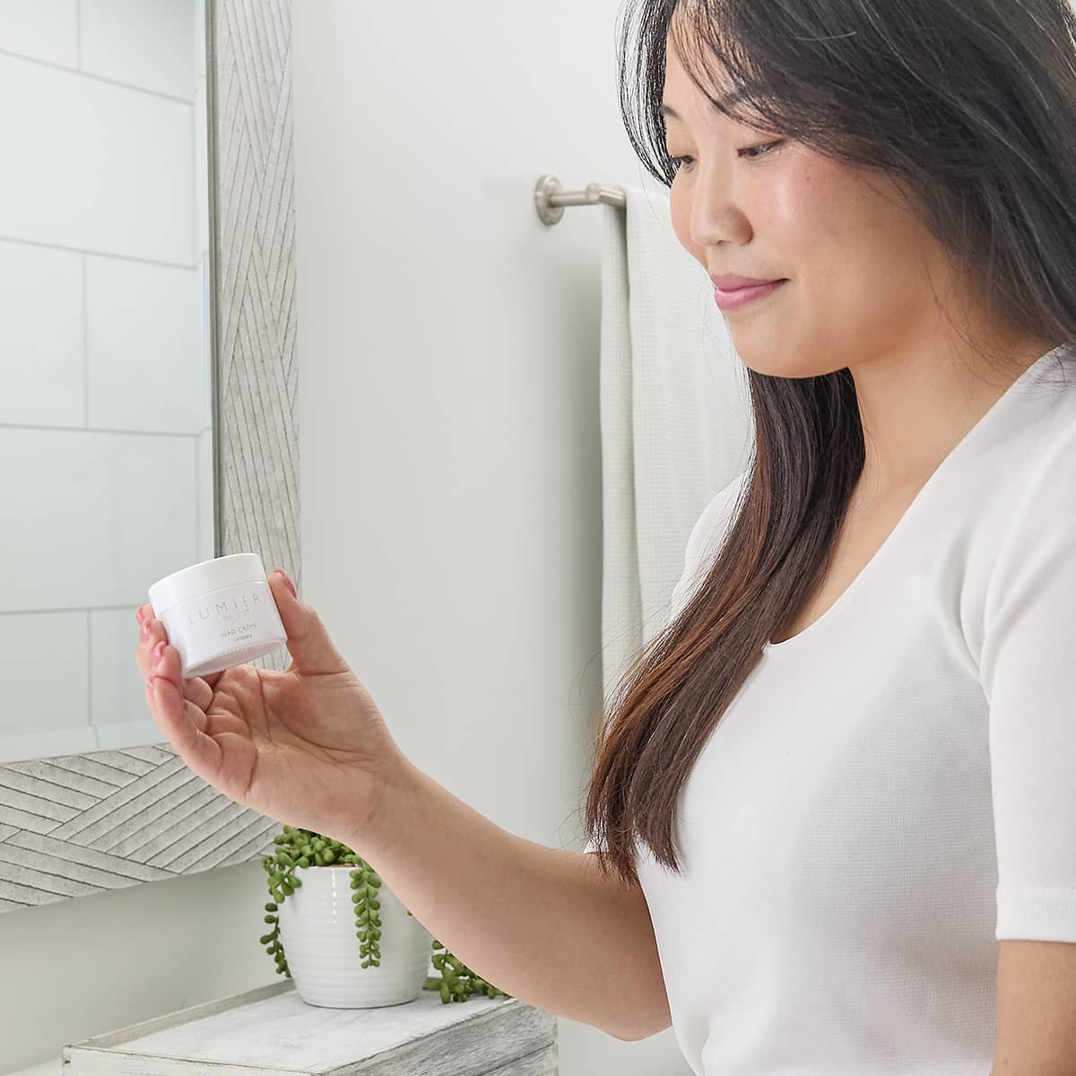 image of a woman holding a canister of Lumiere de Vie NAD Creme