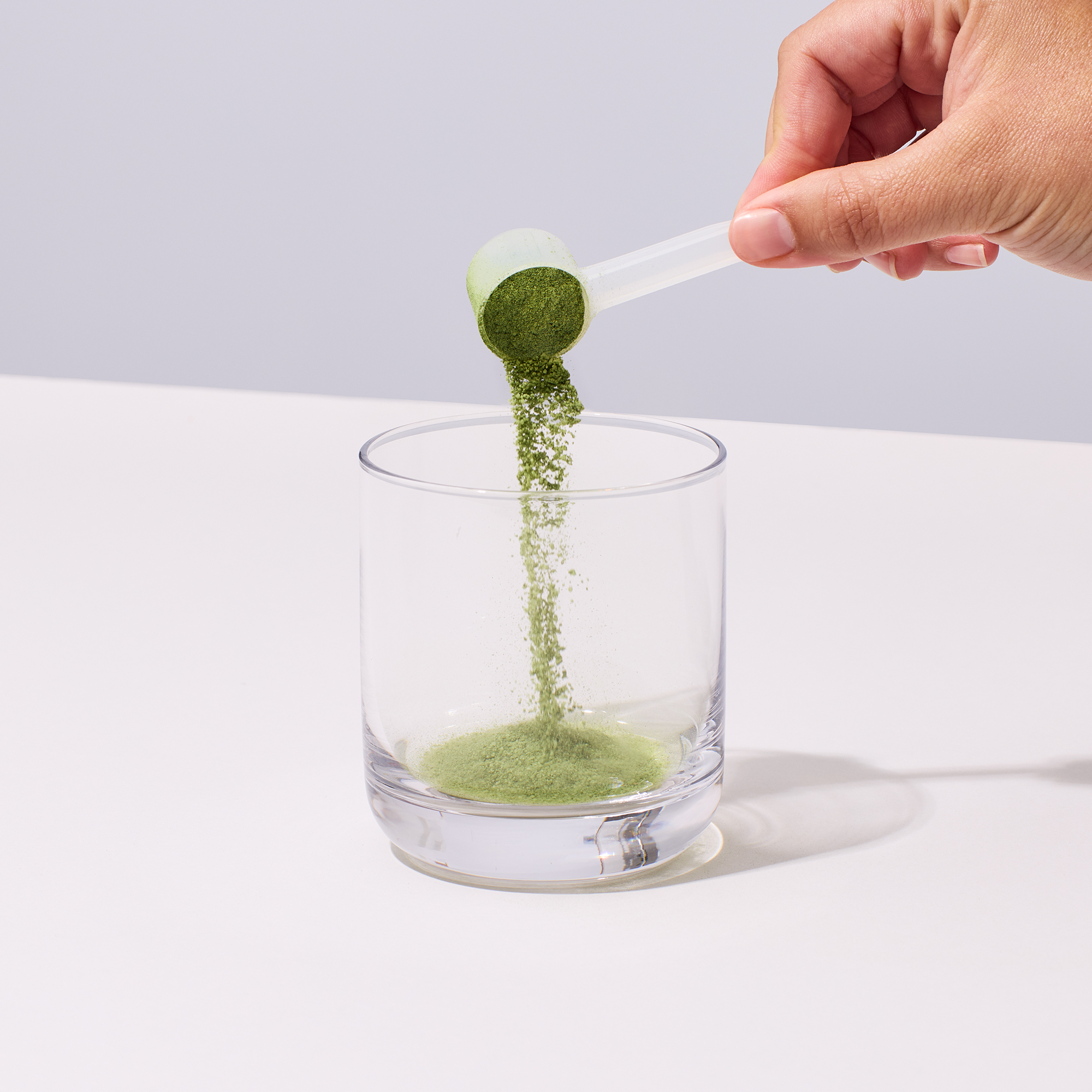 image of person pouring a scoop of IX Complete Greens into a cup