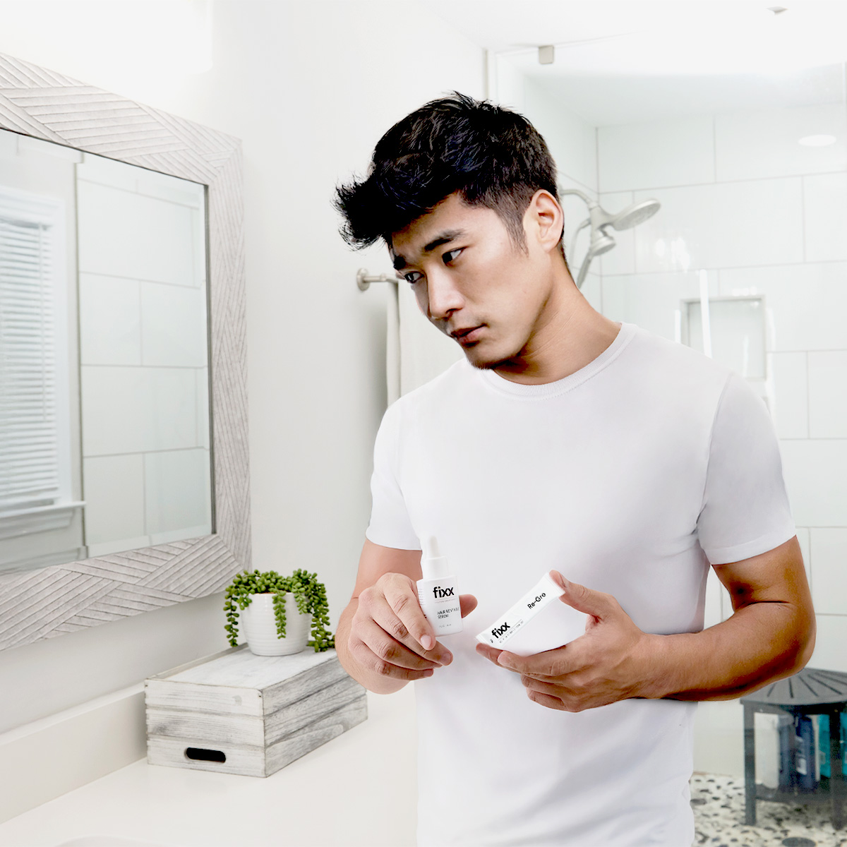 image of man holding Fixx Hair Revival Serum and Fixx Re-Gro