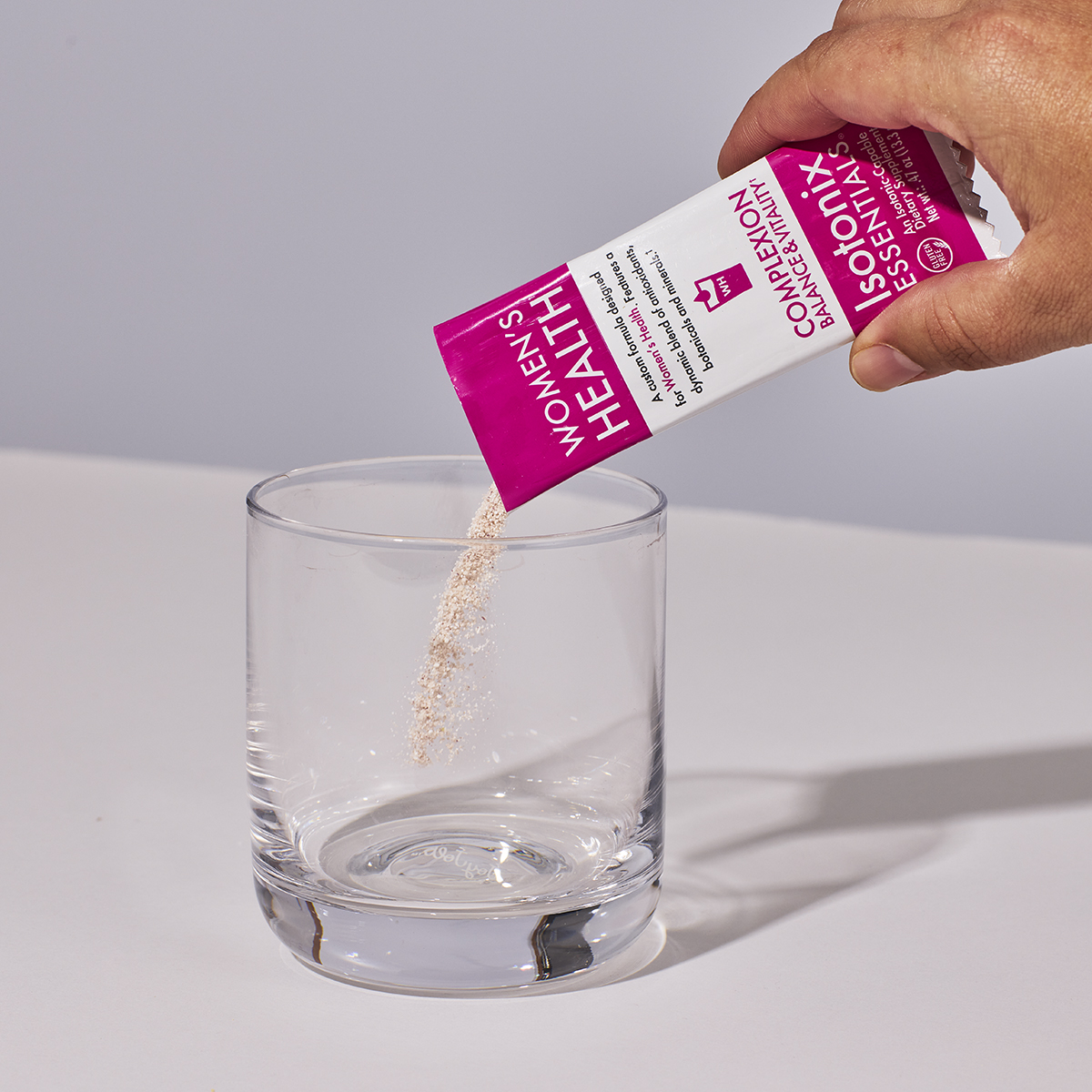 image of someone's hand pouring a packet of Isotonix Women's Health into a glass
