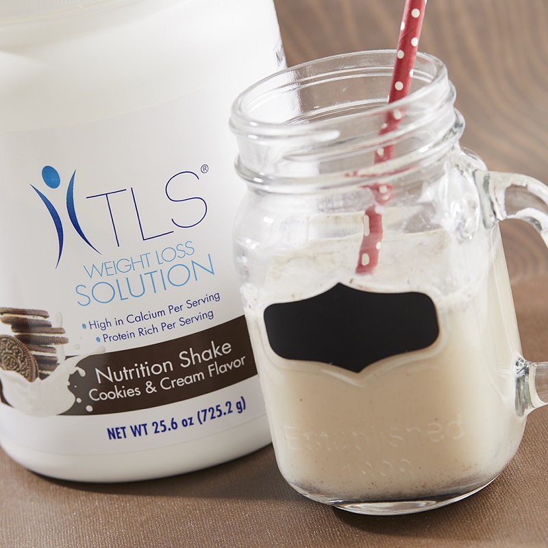 TLS Nutrition Shakes - Cookies & Cream container and glass half filled with product with a straw