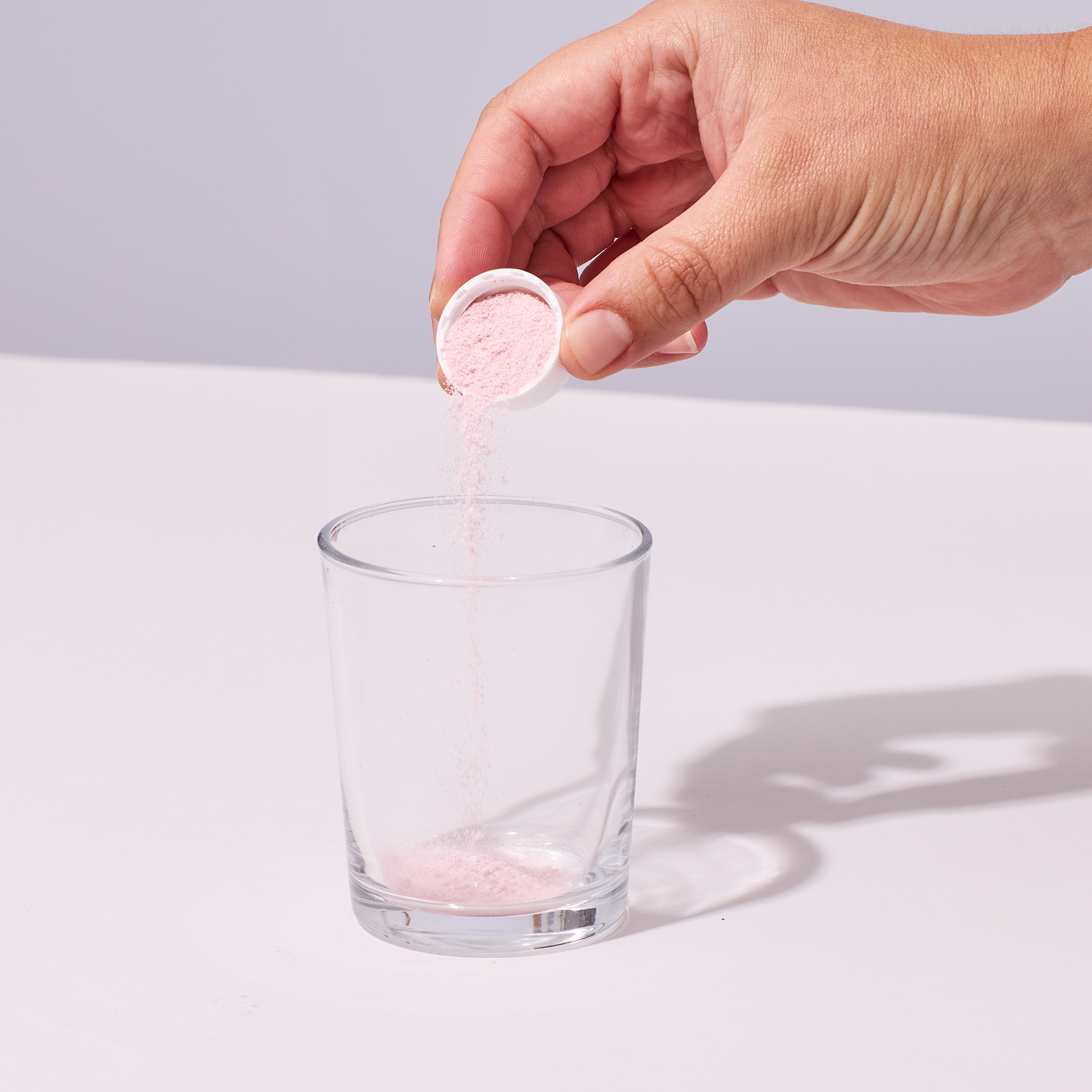image of capful of powder being added to glass