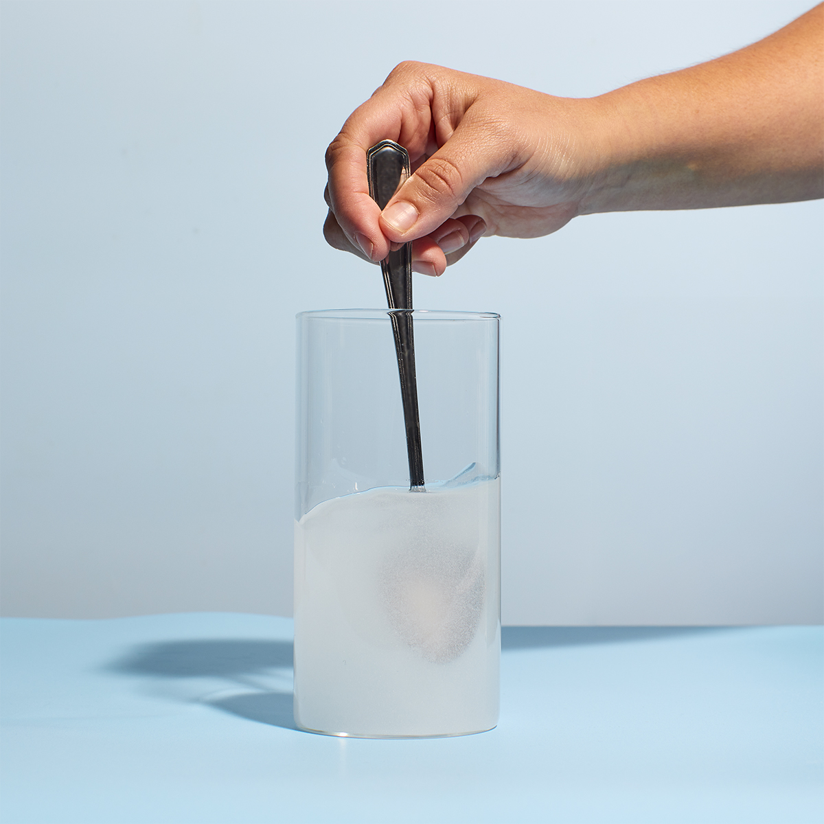 image of woman adding water to glass