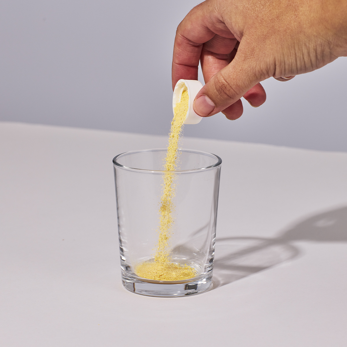 image of person adding capful of powder to glass