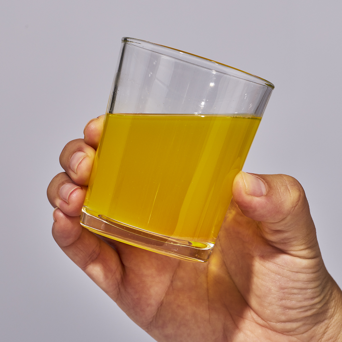 Image of someone's hand holding a glass containing one serving of Isotonix Multivitamin Fifty Plus.