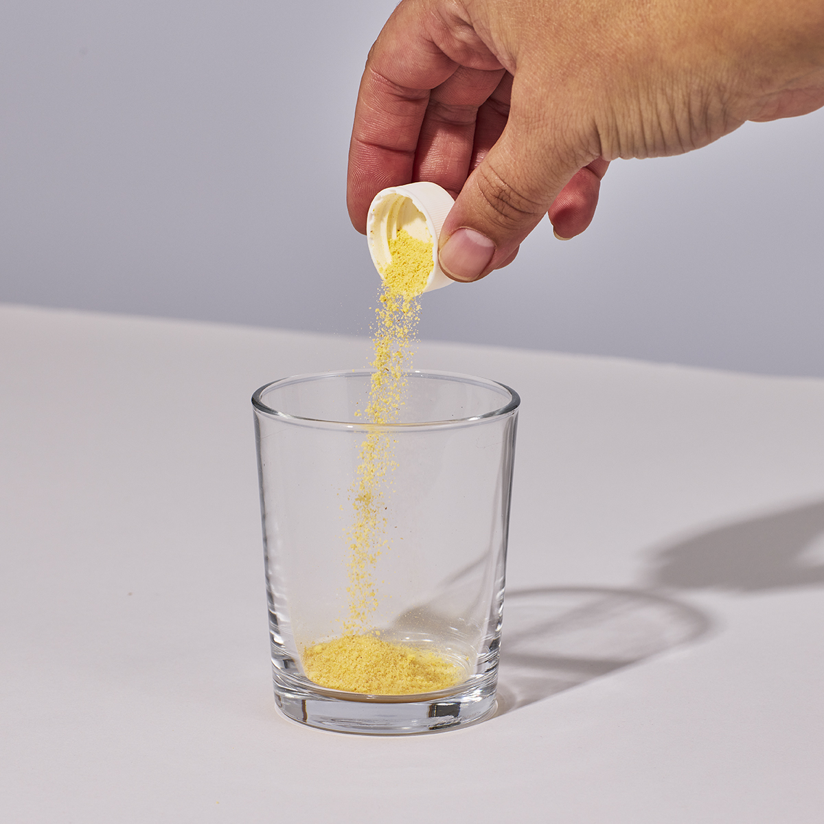 image of capful of powder being added to glass